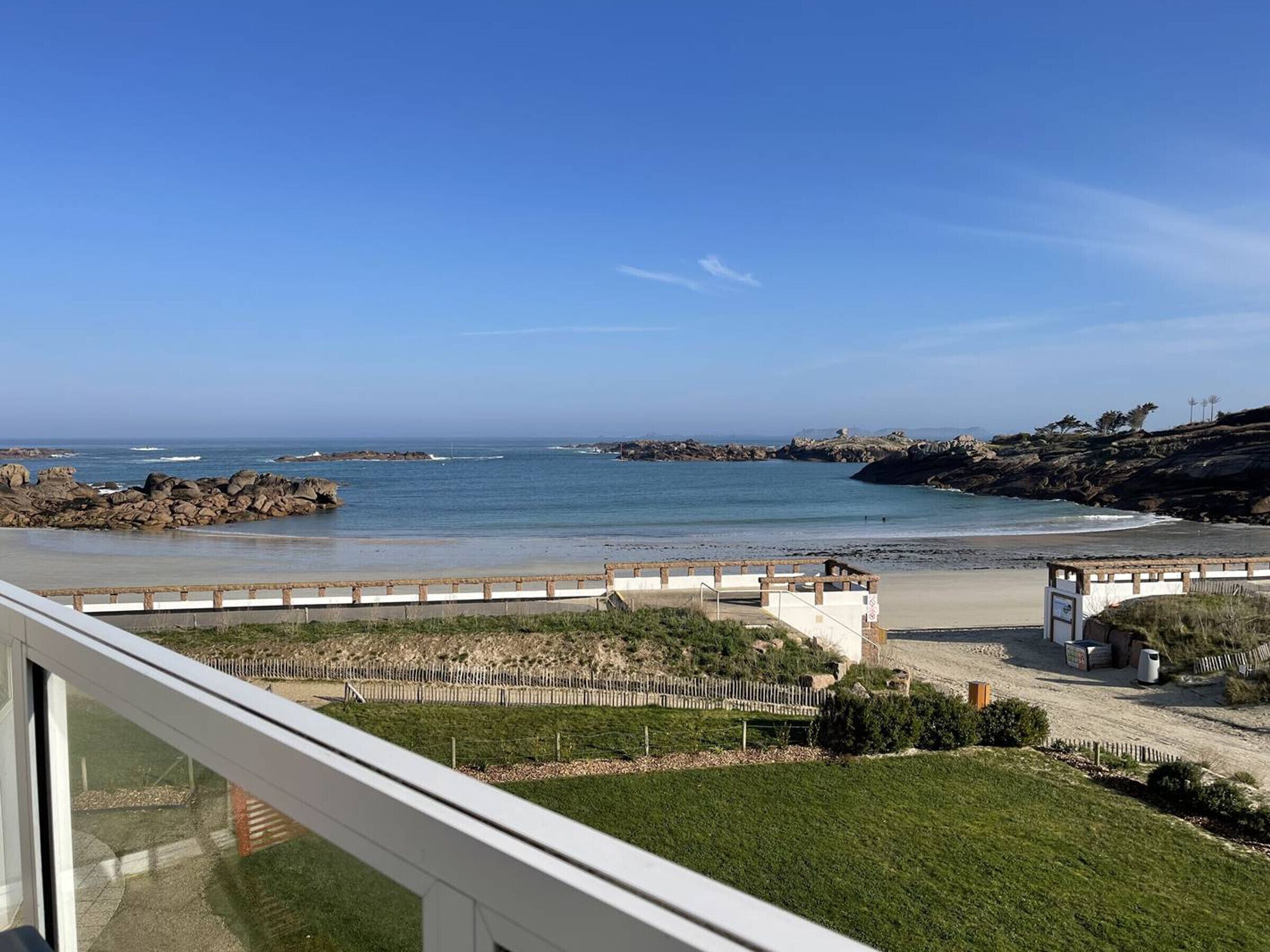 Une vue sur la côte, avec un rivage rocheux, une promenade en bois et une zone herbeuse.