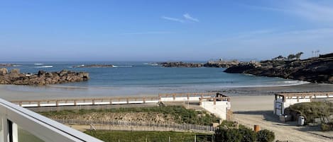 A coastal view with a rocky shoreline, a wooden walkway, and a grassy area.