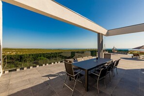 A terrace with a table and chairs, overlooking a scenic landscape.