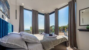 Une chambre d’hôtel moderne dotée d’un grand lit, de nombreuses fenêtres et offrant une vue sur l’extérieur.
