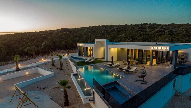 Une villa moderne dotée d’une piscine, d’un espace salon extérieur et offrant une vue sur la forêt environnante.