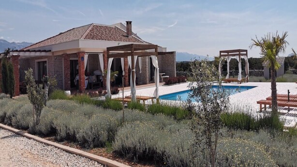 Una casa con piscina, terraza cubierta y vistas a las montañas.