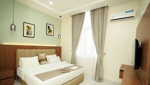 Habitación de hotel con una cama grande, un televisor de pantalla plana, aire acondicionado y obras de arte en las paredes.