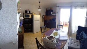 A compact kitchen with a microwave, refrigerator, and a small dining area with a table and chairs.