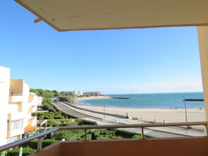 Ein Balkon mit Blick auf einen Strand, eine Straße und Gebäude im Hintergrund.