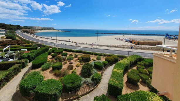A coastal road with a beach and a landscaped garden.