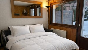 Una cama bien hecha con ropa blanca en una habitación con paredes de madera y un ventanal grande.