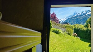 Una ventana con vista a un paisaje verde, una montaña y un edificio.