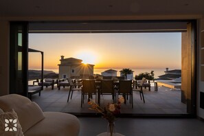 A modern interior with a large glass door leading to a terrace with a sunset view. - Villa CARRERA by Abahana Villas (Benitachell)