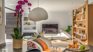 A modern living room with a sofa, a coffee table with pastries, a book, and a decorative orchid. - Villa CARRERA by Abahana Villas (Benitachell)