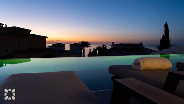 A poolside view with lounge chairs and a sunset. - Villa CARRERA by Abahana Villas (Benitachell)