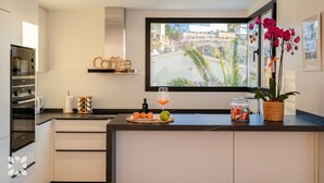 A modern kitchen with a large window, a coffee sign, and a decorative orchid plant. - Villa CARRERA by Abahana Villas (Benitachell)