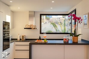 A modern kitchen with a large window, a coffee sign, and a decorative orchid plant. - Villa CARRERA by Abahana Villas (Benitachell)