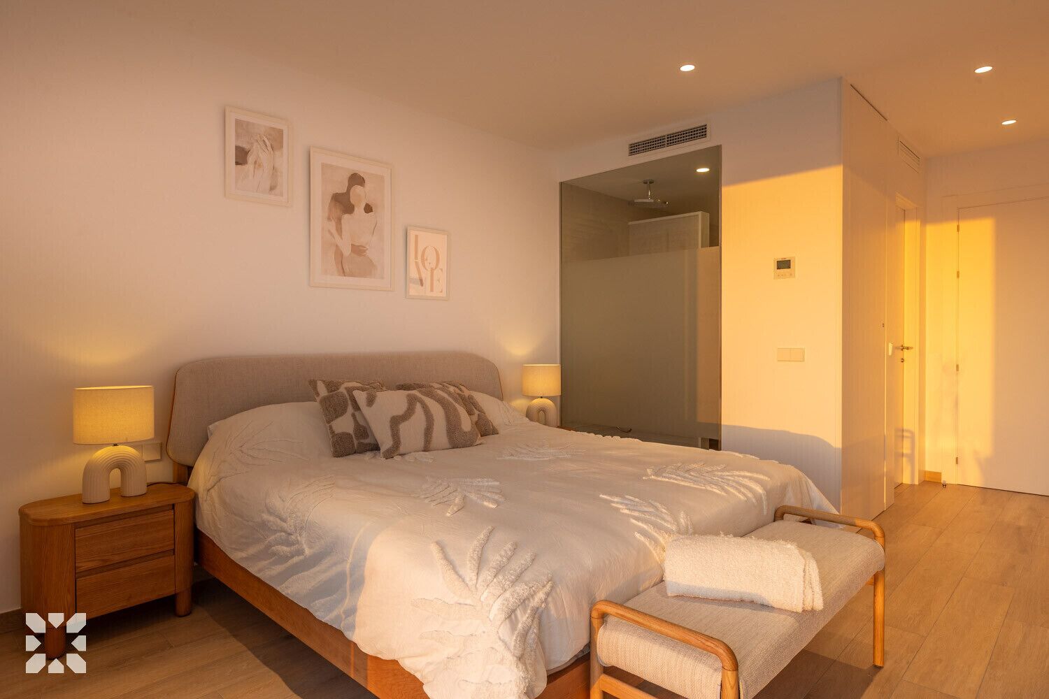 A bedroom with a bed, bedside tables, a bench, and a large mirror.