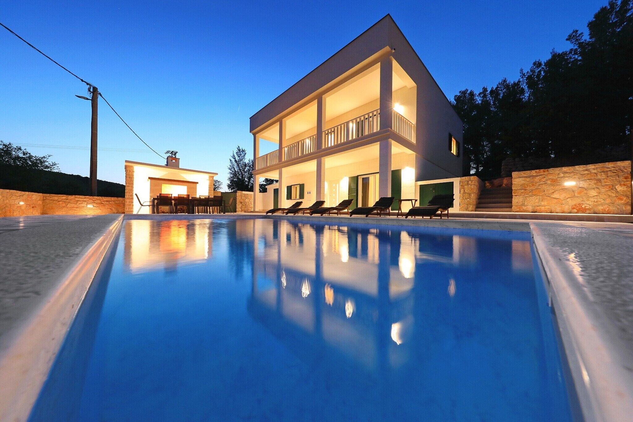 Une maison moderne à deux étages avec une piscine située au premier plan.