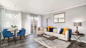 Ein Wohnzimmer mit einem weißen Sofa, blauen Sesseln, einem Couchtisch und einer Lampe.