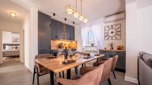 A modern kitchen with grey cabinets, a wooden dining table, and a pendant light. - Villa near Zrmanja's canyon (Pridraga)