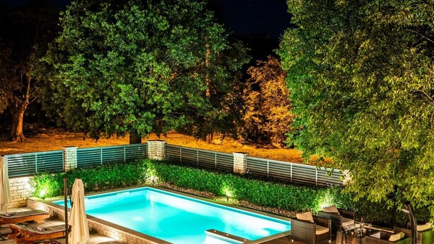 A swimming pool with lounge chairs and a patio area, surrounded by trees and a brick wall. - Villa near Zrmanja's canyon (Pridraga)