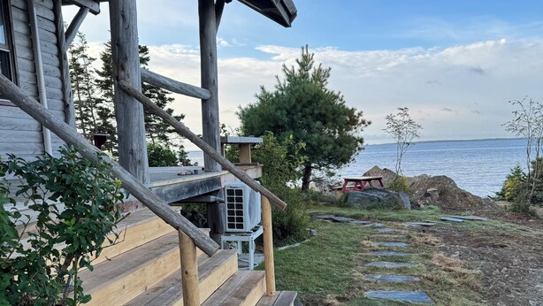 Een houten trap die leidt naar een veranda met uitzicht op zee.
