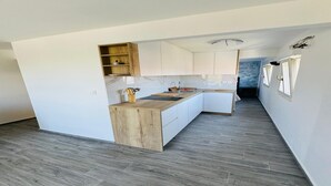 Moderni keittiö, jossa on valkoiset kaapit, puinen työtaso ja marmorista tehty välitila.