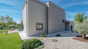 A modern two-story building with a flat roof, large windows, and a gravel driveway. - Villa Kalea with pool (Marceljani)