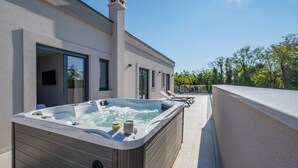 A modern building with a hot tub on the patio, large windows, and a clear sky. - Villa Kalea with pool (Marceljani)