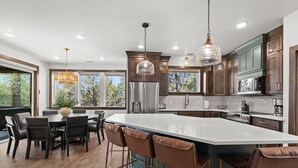 A modern kitchen with a large island, dark wooden cabinets, stainless steel appliances, and pendant lighting. - East Zion New Build, Sleeps 12, Hot Tub, Rooftop Fire Pit & Game Room (Orderville)