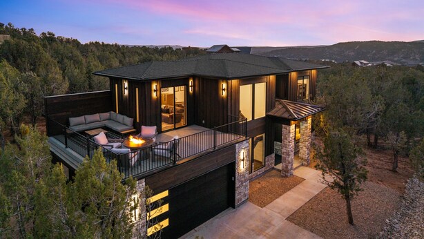 A modern two-story house with a balcony, large windows, and a stone foundation. - East Zion New Build, Sleeps 12, Hot Tub, Rooftop Fire Pit & Game Room (Orderville)