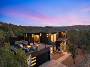 A modern two-story house with a balcony, large windows, and a stone foundation. - East Zion New Build, Sleeps 12, Hot Tub, Rooftop Fire Pit & Game Room (Orderville)
