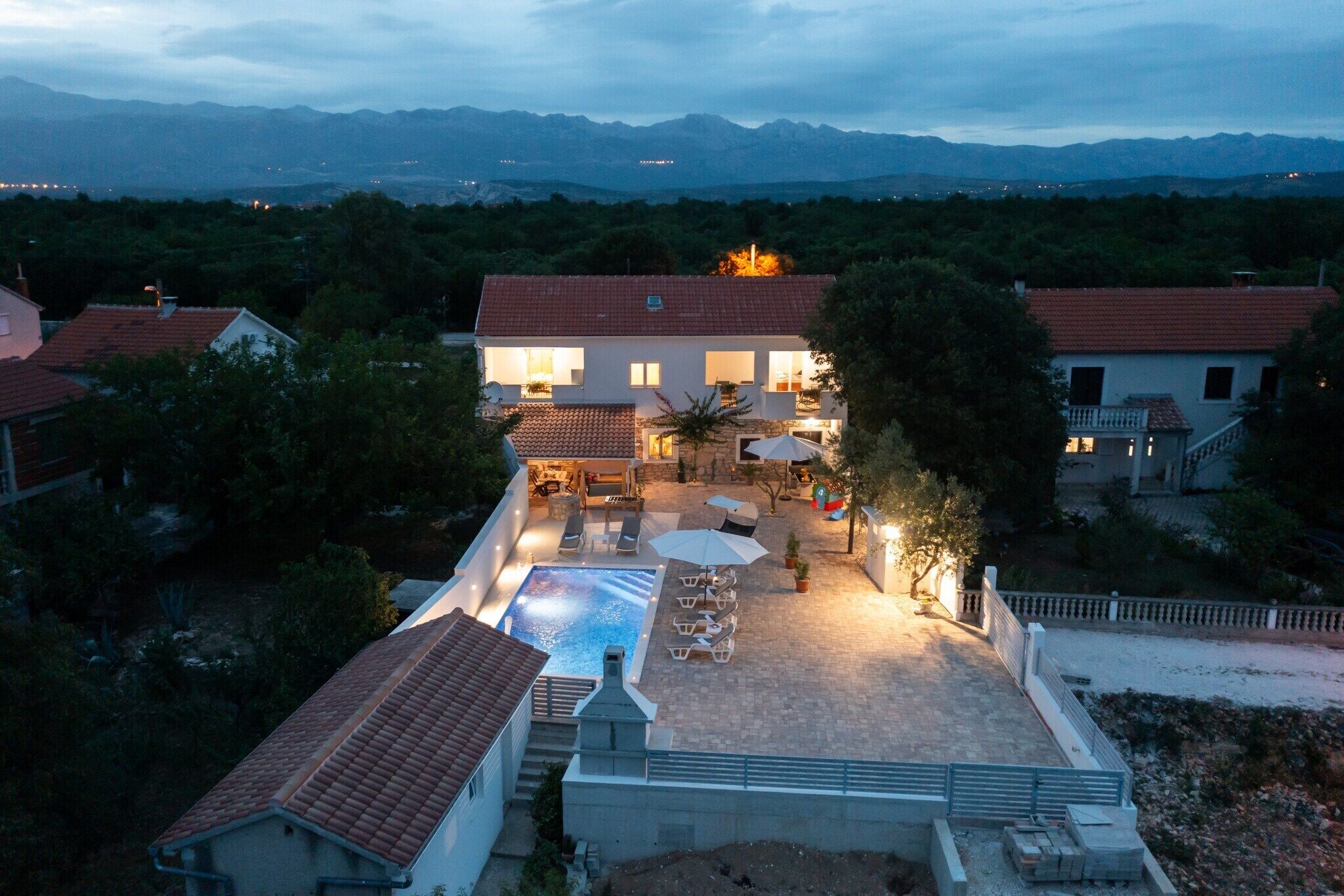 Una villa con piscina, mobiliario exterior y vistas a las montañas.