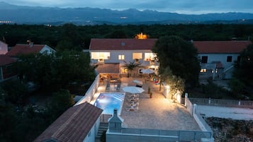 Una villa con piscina, mobiliario exterior y vistas a las montañas.