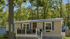 A single-story mobile home with a porch, a small deck, and a gravel driveway. - GOTL Retreat, short walk to strip, 15 min to Spire (Geneva on the Lake)