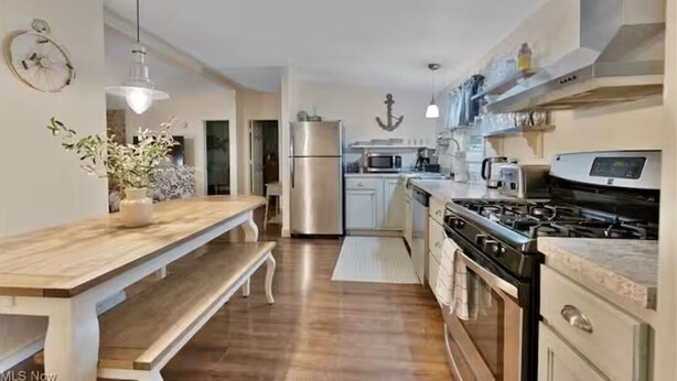 A modern kitchen with stainless steel appliances, a wooden dining table, and a bench. - GOTL Retreat, short walk to strip, 15 min to Spire (Geneva on the Lake)