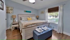 A bedroom with a bed, a ceiling fan, a window with curtains, and a nightstand with a lamp. - GOTL Retreat, short walk to strip, 15 min to Spire (Geneva on the Lake)