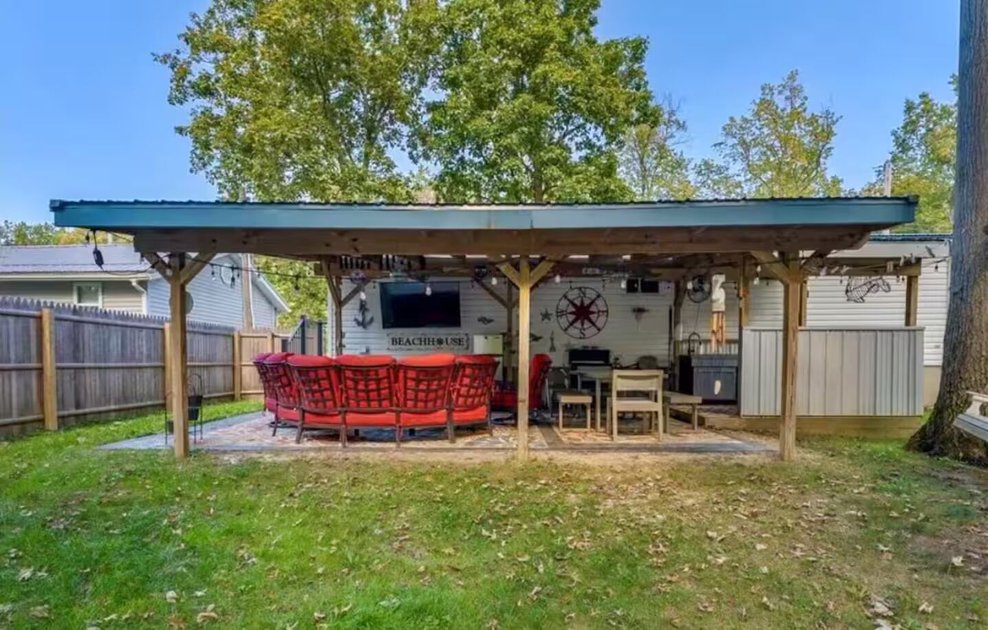 En täckt uteplats med ett biljardbord, röda, vadderade sittplatser och en tv-skärm.