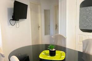 A room with a round glass table, a potted plant, a TV mounted on the wall, and a door leading to another room. - Apartment Moreno 2 with seaview (Poljica)