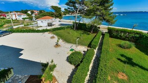 A coastal property with a paved driveway, a lawn, and a view of the sea.