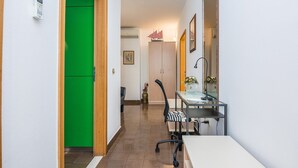 A narrow hallway with a green door, a small table with a vase, and a chair. - Seaside Tranquil Stay for 4 (Vir)