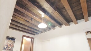 A room with exposed wooden beams, a white ceiling, and a poster of Carnevale di Venezia. - Appartamento Sestiere Castello by Ca-Sa Check (Venezia)