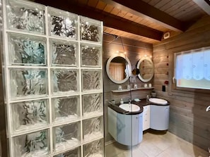 A bathroom with a glass block wall, two sinks, and wooden paneling. - Murmure du ruisseau-10 person chalet with sauna - La Bresse (La Bresse)