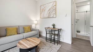 Uma sala de estar moderna com sofá, mesa de centro e área de jantar com cadeiras.