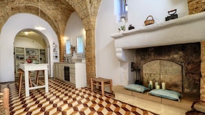 A kitchen with a stone fireplace, a dining area with a bench, and a patterned floor. - Altra Meta Palace by LoveSud (Gagliano del Capo)