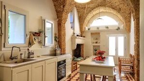 A kitchen with a stone arch, a sink, cabinets, and a dining area with a table and chairs. - Altra Meta Palace by LoveSud (Gagliano del Capo)