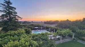 A pool area with a view of the sunset, surrounded by greenery and trees. - Altra Meta Palace by LoveSud (Gagliano del Capo)