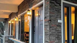 Un edificio con fachada de piedra, varias puertas y un balcón con barandilla.