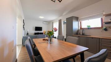 A modern kitchen with a wooden table, chairs, and a vase with flowers.