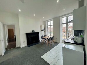 A modern kitchen with a dining area, a fireplace, and large windows. - 402-404 Commercial road (london)