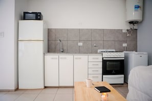 A compact kitchen with a refrigerator, microwave, stove, and washing machine.