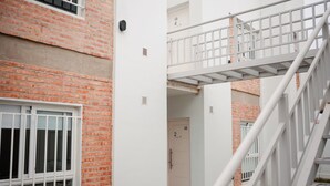 A multi-level building with brick and white walls, a white staircase, and numbered doors. - Home office apartment with a fully equipped, comfortable desk, Roca (General Roca)