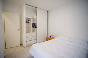 A bedroom with a bed, a wardrobe, and a nightstand.